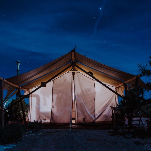 a canvas safari tent glowing under the night sky stars