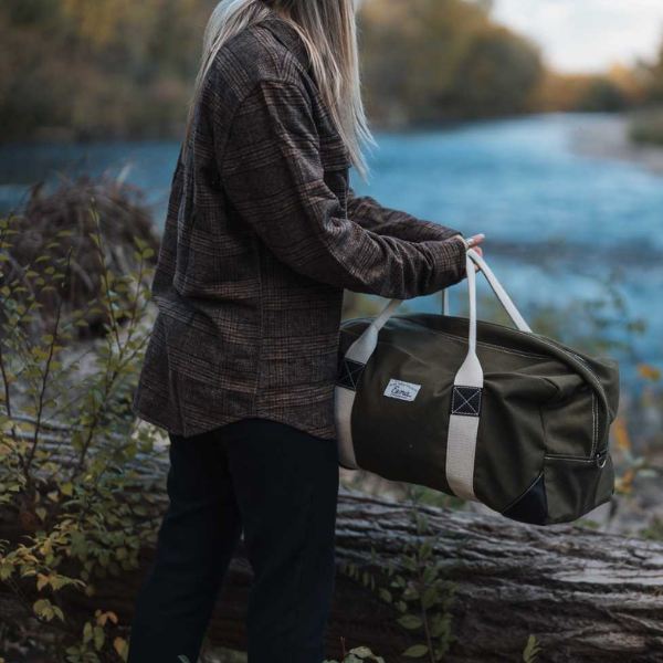 women holding duffel bag near a river