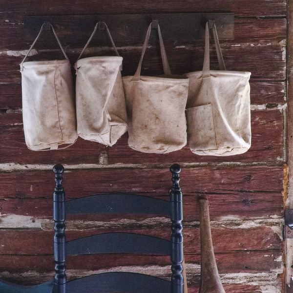 canvas bags for firewood hanging above chair in log cabin