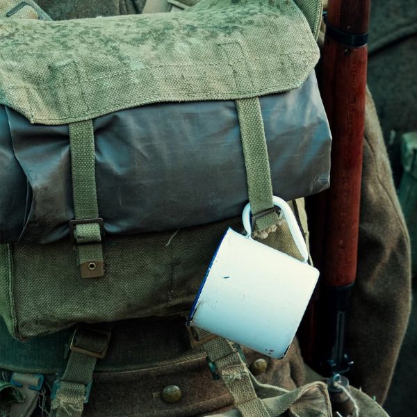 canvas bedroll on a backpack with enamel mug