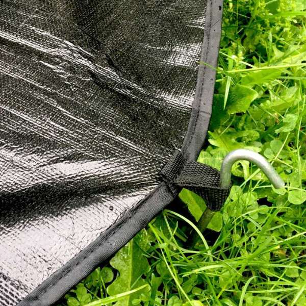 black tent footprint groundsheet staked into green grass 