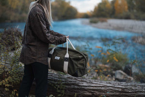 duffel bag in hand near river and log