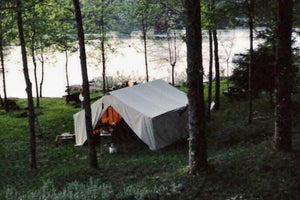 wall tent under trees with lake in background